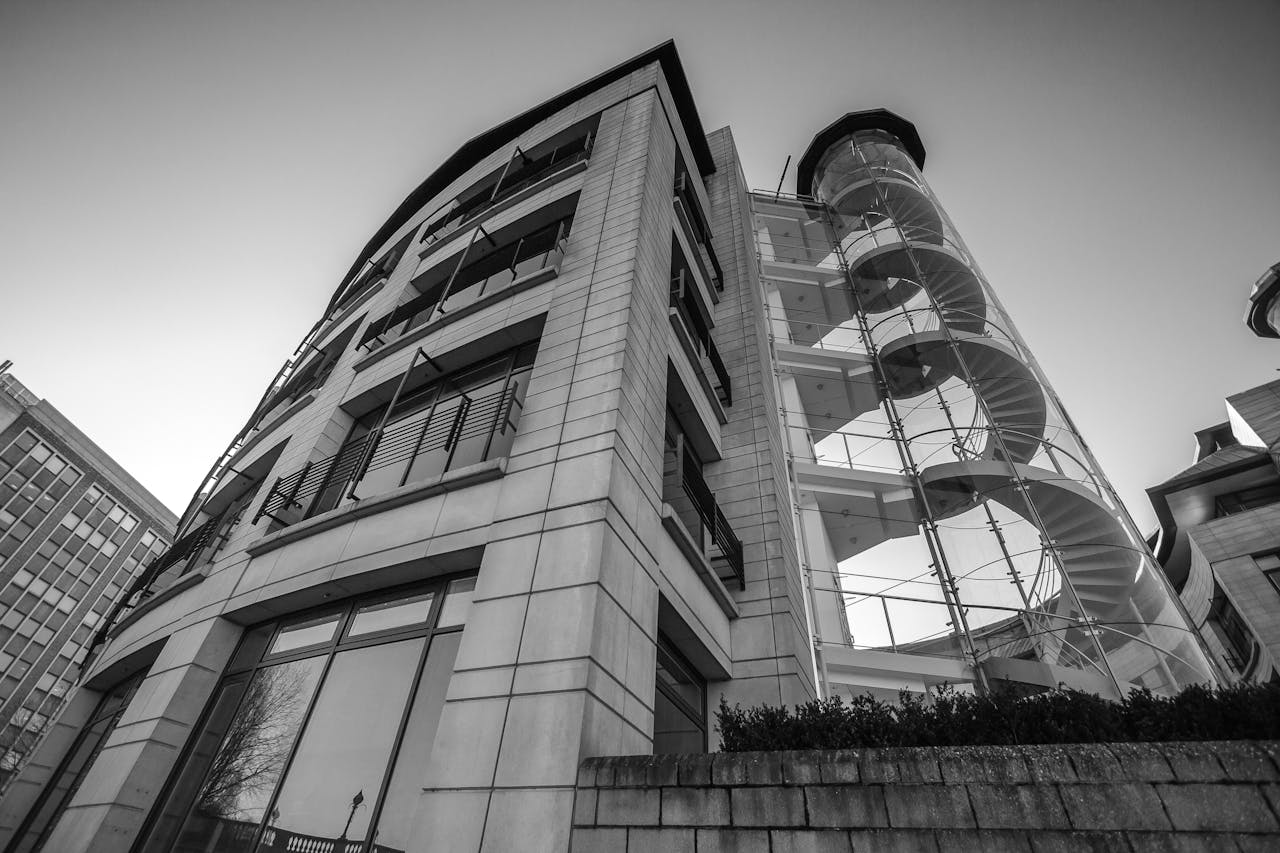 Black and white view of a modern urban building with a striking spiral staircase.